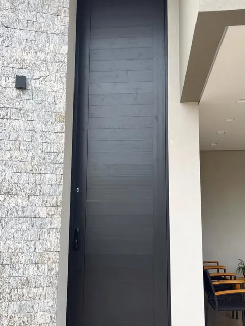 Porta pivotante preta de grande altura em fachada residencial